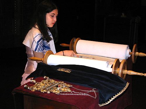 Kara reads the Hebrew text from the torah roll.